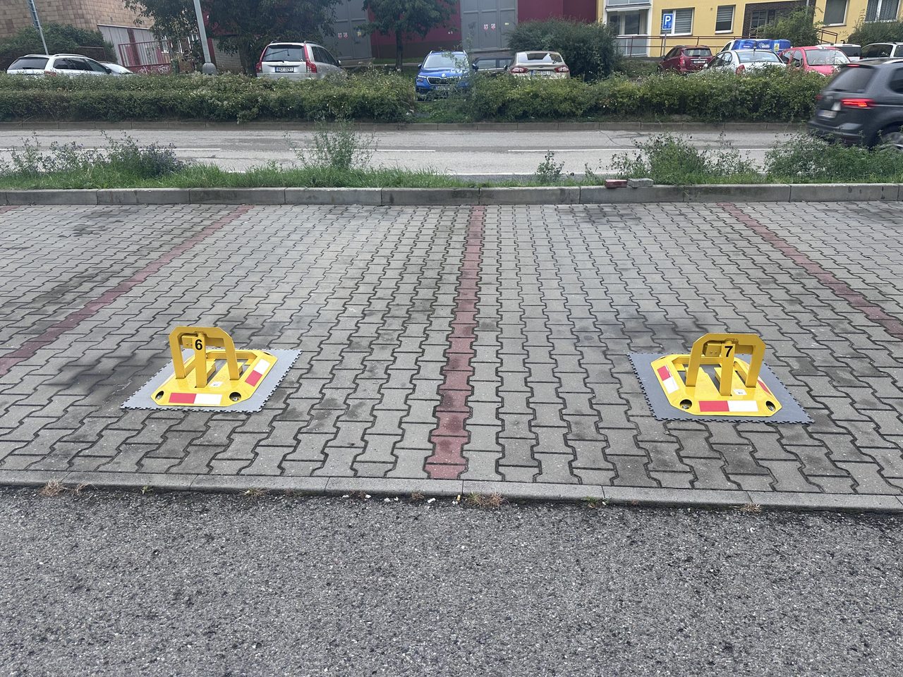 Detail dvou zamykatelných parkovacích zábran označených čísly míst 6 a 7